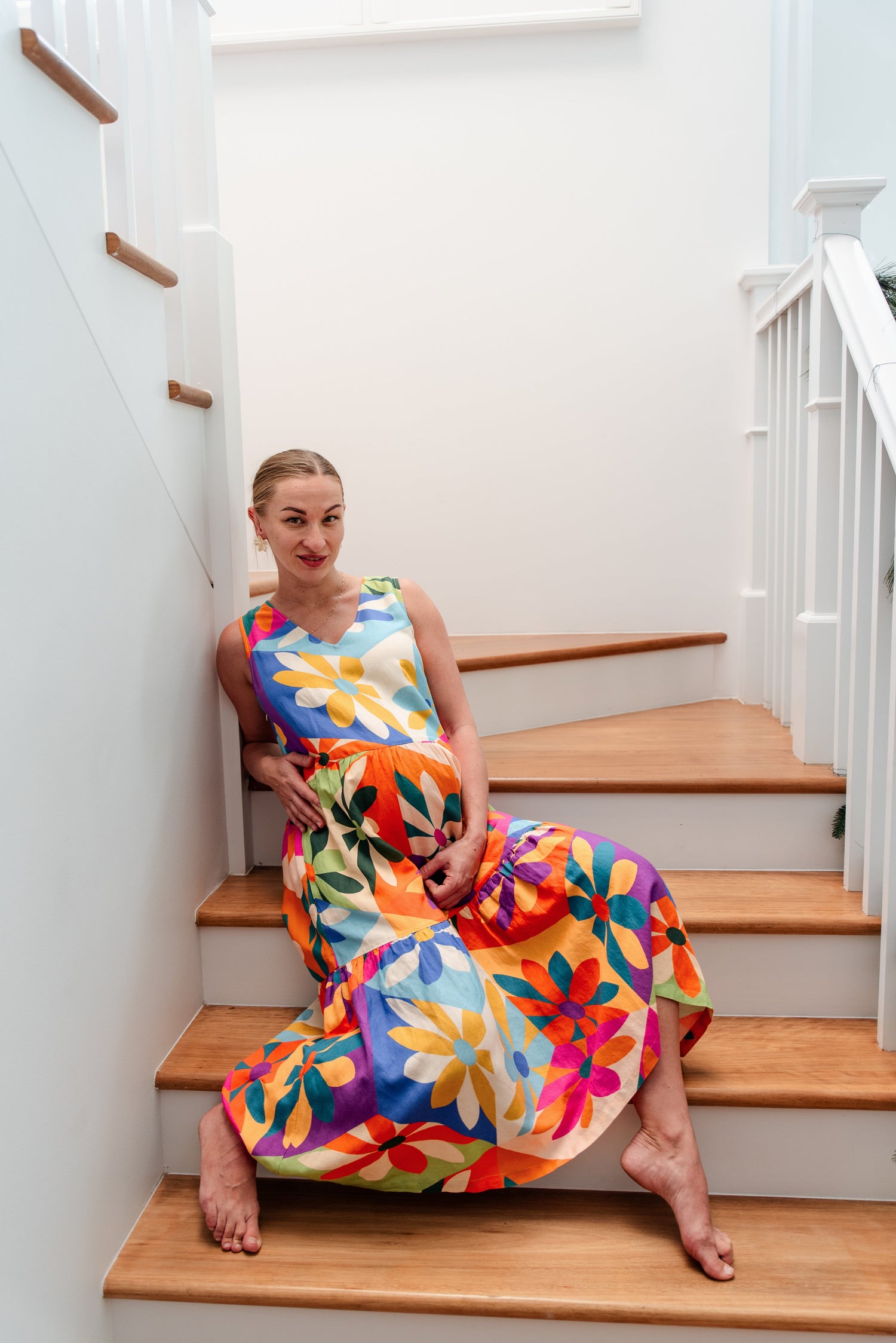 Pregnant woman wearing the Harper Dress Geometric sitting on a staircase.